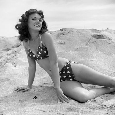 1950s-1960s Brunette Bathing Beauty Stretched Out On Sand Wearing Polka-Dot Bikini Looking At Camera Print By Vintage