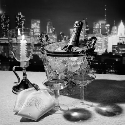 1970s Champagne Bottle In Ice Bucket With Glasses Candle & Napkins On Table & New York City Night Skyline In Background