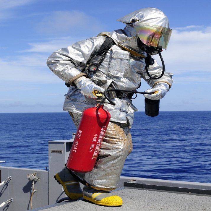 Posterazzi Firefighter carries a CO2 fire extinguisher onto the flight deck of USS Denver Poster Print, (12 x 16)