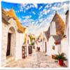 CORFOTO 117x78 Inch Italy Town Street Tapestry Famous Trulli Houses Sunny Blue Sky Italian Street Wall Background for Europe Themed Party Decor Wedding Bedroom Living Room Dorm Wall Hanging view 1